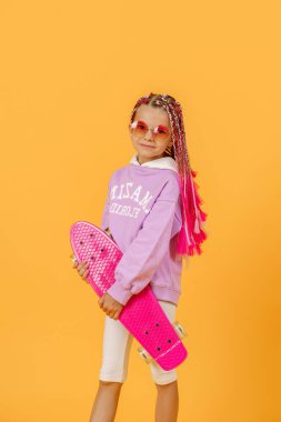 Aktif genç kız pembe gömlekli ve beyaz şortlu elinde kaykayla