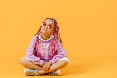Yuvarlak gözlüklü, pembe saçlı şık bir kız oturuyor.