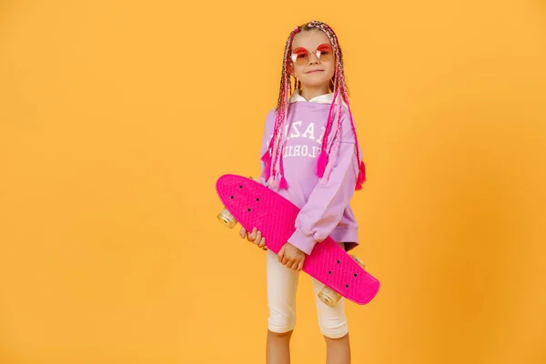 Actief jong meisje in roze shirt en witte shorts met skatebo — Stockfoto