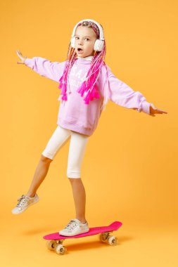 Aktif ve mutlu, kıvırcık saçlı, kulaklıklı, esprili bir kız.