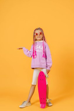 Aktif genç kız pembe gömlekli ve beyaz şortlu elinde kaykayla