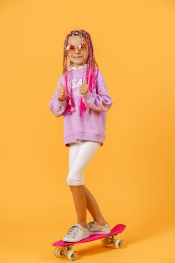 Aktif genç kız pembe gömlekli ve beyaz şortlu elinde kaykayla