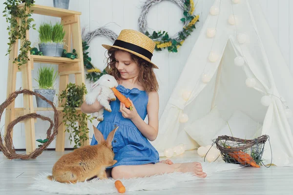 Маленькая милая девочка кормит морковь пушистым домашним кроликом, заботой и жизнью — стоковое фото