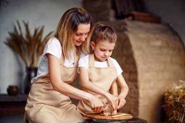 Anne ve kızı kil kaplı, çömlek sanatının keyfini çıkarıyorlar.