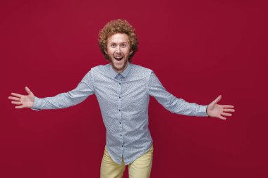 Zarif bir gömlek giyen genç, kıvırcık, olgun bir adam zaferi ya da başarıyı kutluyor, şaşırıyor ve şok oluyor.