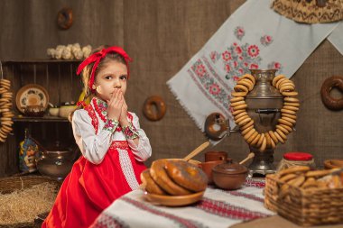 Yemek ve semaver dolu masada oturan sevimli kız. Tra