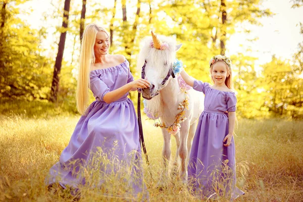 Mãe e filha em vestidos de lavanda semelhantes estão acariciando um un — Fotografia de Stock