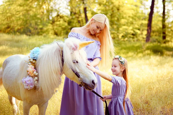 Mother and daughter in similar lavender dresses are petting a un — Stock Photo, Image