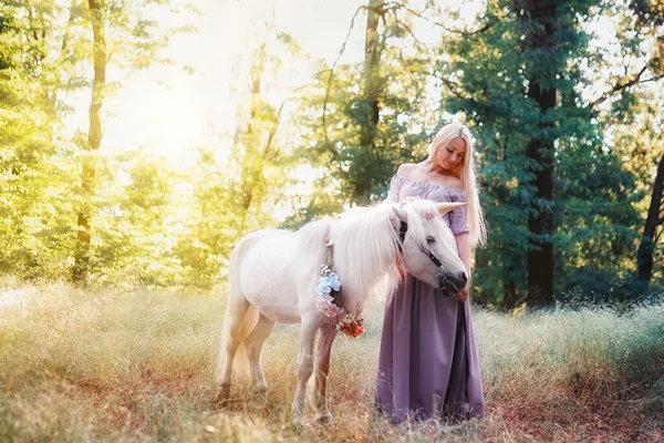 Lila ruhás nő, fehér egyszarvú lovat ölelget. Álmok jönnek. — Stock Fotó