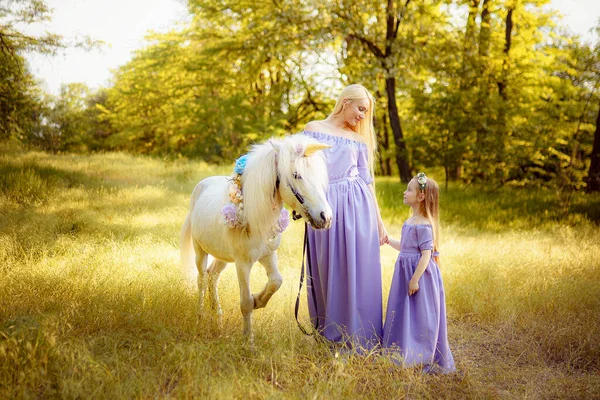 Mãe e filha em vestidos de lavanda semelhantes estão acariciando um un — Fotografia de Stock