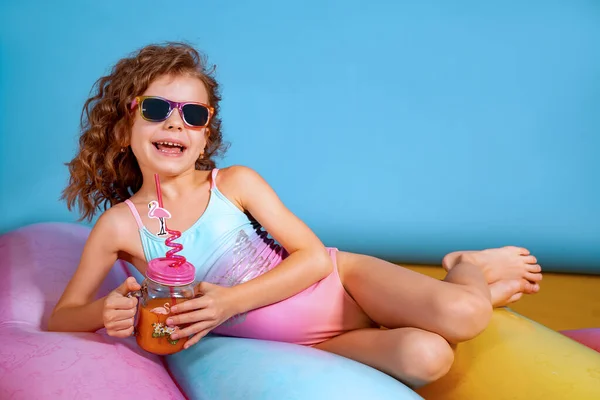 Красива дівчина в барвистому купальнику і сонцезахисних окулярах тримає пенью — стокове фото
