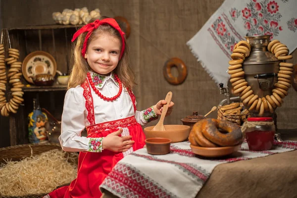 Menina adorável sentada à mesa cheia de comida e grande samovar. Tra — Fotografia de Stock