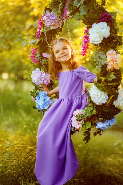 Милая маленькая девочка в сиреневом платье позирует сидя в Рине — стоковое фото