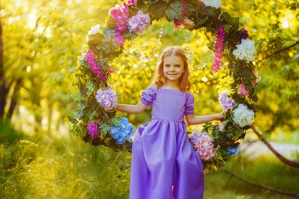 漂亮的小女孩穿着淡紫色的衣服摆姿势坐在森林里 — 图库照片