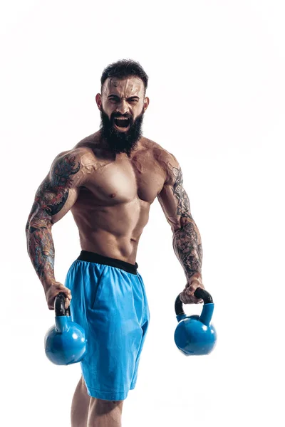 Muscular bodybuilder guy doing exercises with kettlebells over w — Stock Photo, Image