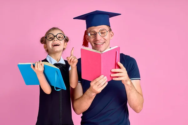 Homem em chapéu acadêmico segurando livro, estudar junto com bonito prete — Fotografia de Stock