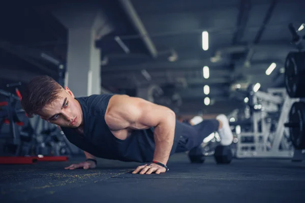 Een jonge atleet die push-ups doet in de sportschool. Spierachtige en sterke gu — Stockfoto