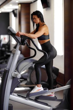 Spor salonunda antrenman. Spor salonunda kız antrenörü. Step makinesinde çalışıyor.