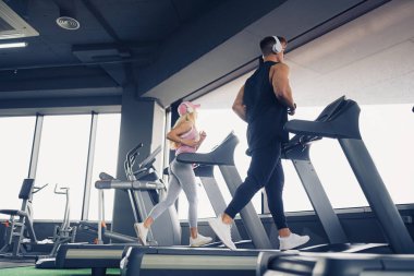 Müzik ve egzersizler birlikte gider. Koşu bandında çalışan çift. Erkeğe odaklan.