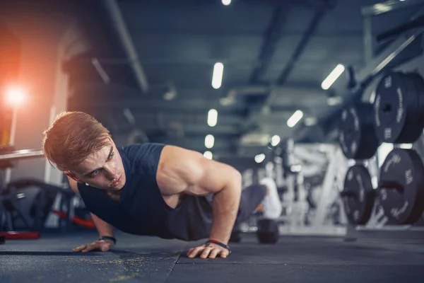 Spor salonunda şınav çeken genç bir sporcu. Güçlü ve kaslı. — Stok fotoğraf