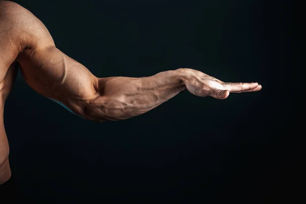 Brazo tenso, venas, músculos del culturista sobre un fondo oscuro, aislar — Foto de Stock