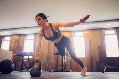 Genç motive olmuş bir kız spor salonunda kettlebell kullanıyor, uzun bir fotoğraf, fotokopi alanı.