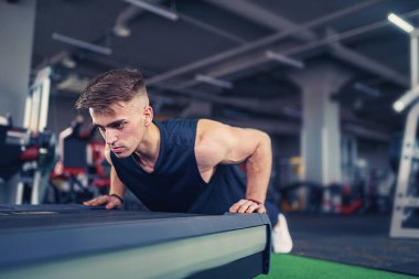 Spor salonunda şınav çeken genç bir sporcu. Güçlü ve kaslı.