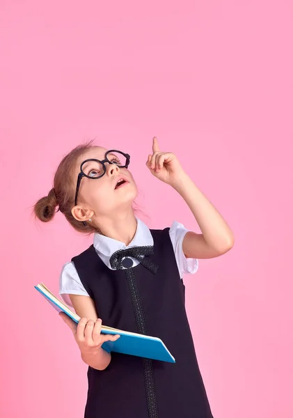 Fille préscolaire avec des lunettes tenant un livre, leva la main et — Photo