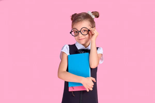 Ragazzina carina con occhiali e libri su sfondo rosa, spac — Foto Stock