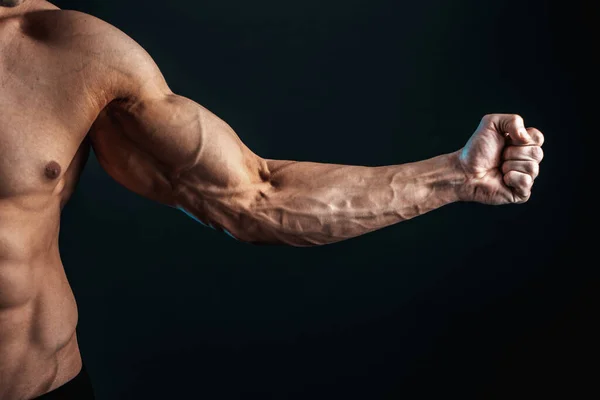 Spänd arm knuten i knytnäve, vener, bodybuilder muskler på en mörk bakgrund, isolat — Stockfoto