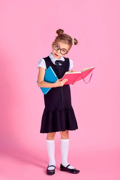 Linda niña con gafas y libros sobre fondo rosa, spac —  Fotos de Stock