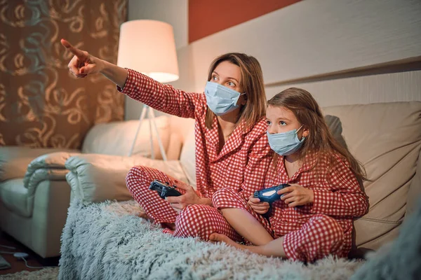 Woman and young girl wearing pajamas and medical protective mask