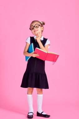 Gözlükleri ve pembe arka plan kitapları olan sevimli küçük bir kız.