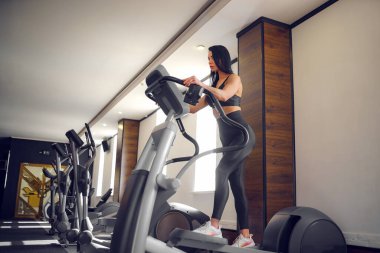 Spor salonunda antrenman. Spor salonunda kız antrenörü. Step makinesinde çalışıyor.