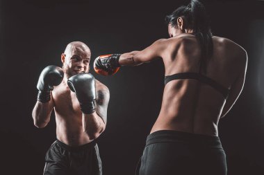 Üstsüz kadın boks antrenörüyle egzersiz yapıyor ve kendini savunuyor.