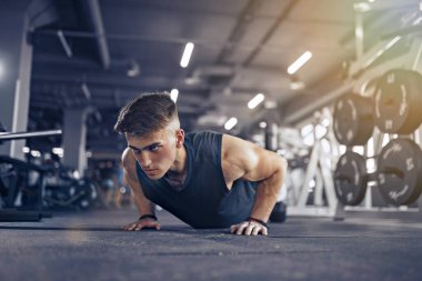 Vücut geliştirme treninin bir parçası olarak şınav çeken genç bir atlet.