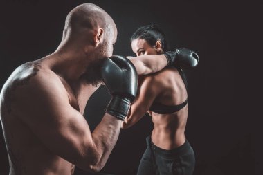 Üstsüz kadın boks antrenörüyle egzersiz yapıyor ve kendini savunuyor.