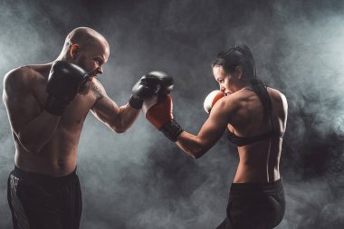 Üstsüz kadın boks antrenörüyle egzersiz yapıyor ve kendini savunuyor.