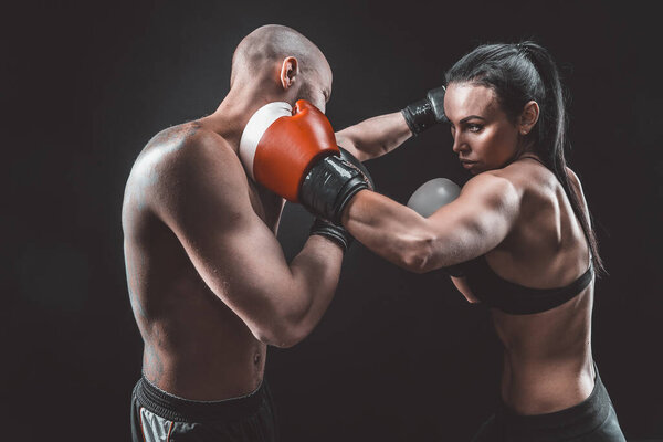 Женщина без рубашки тренируется с тренером по боксу и самообороне