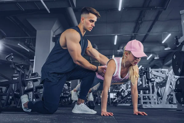 Fitness instructor help girl to do push ups on training in fitne — Stock Photo, Image