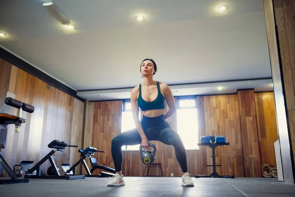 Junge erwachsene Fitness-Frau macht Schaukelgymnastik mit einer Kettlebell — Stockfoto
