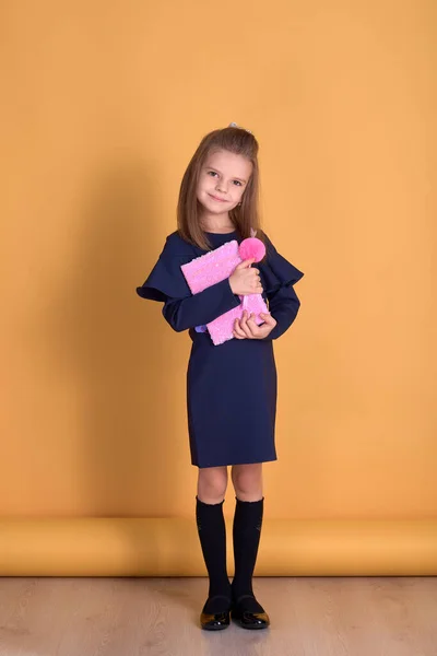 Niña de la escuela primaria en uniforme lleva un cuaderno en sus manos smi —  Fotos de Stock