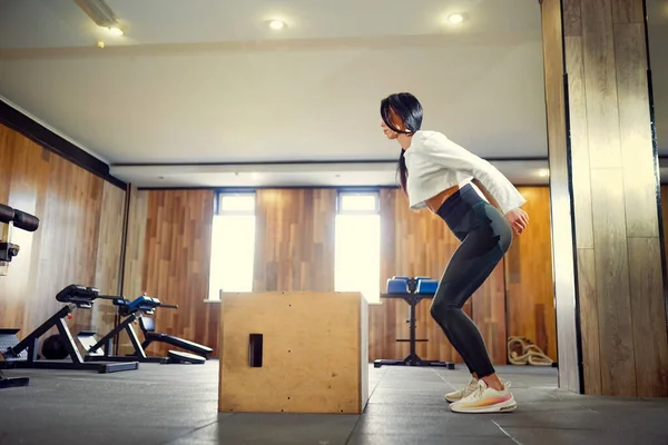 Aufnahme einer jungen Frau, die mit einer Schachtel im Fitnessstudio trainiert. Weiblich bei — Stockfoto