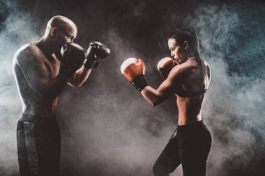 Üstsüz kadın boks antrenörüyle egzersiz yapıyor ve kendini savunuyor.