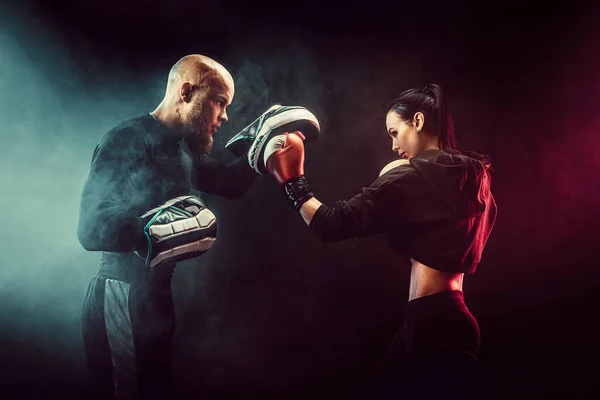 Mujer haciendo ejercicio con entrenador en la lección de boxeo y defensa personal — Foto de Stock