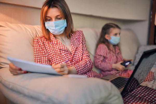 Kvinna i pyjamas med anteckningsbok och papper som arbetar hemifrån — Stockfoto