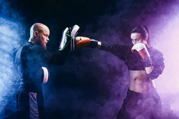 Mujer haciendo ejercicio con entrenador en la lección de boxeo y defensa personal — Foto de Stock