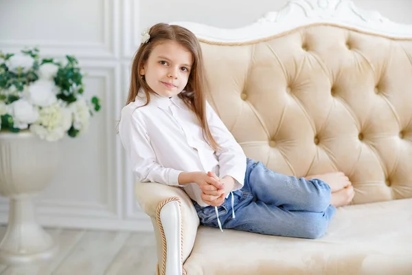 Pequena menina bonito encontra-se no sofá na sala — Fotografia de Stock