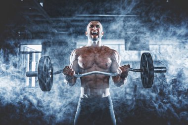 Spor salonunda spor yapan kaslı bir adam, pazularıyla egzersiz yapıyor. Güçlü erkek, çıplak karın kasları var.