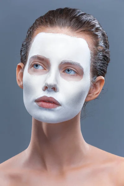 Belle fille est appliquée un masque cosmétique blanc à partir de points noirs. Isoler, studio — Photo